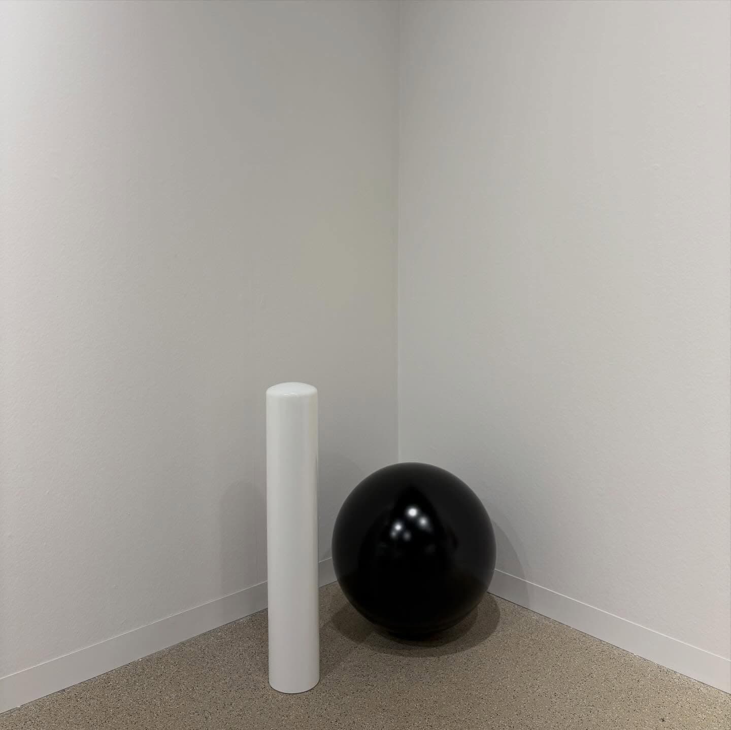 A black sphere and a white column in a corner